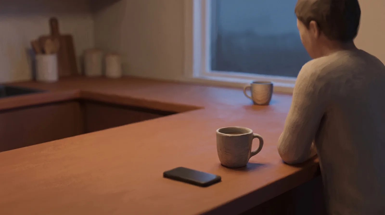 Two mugs on a kitchen counter at dusk, one near a face-down phone, evening light through a window.